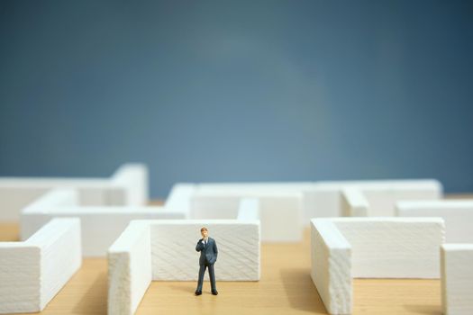 Business strategy conceptual photo - Miniature of businessman looking for solution on a labyrinth maze. Image photo