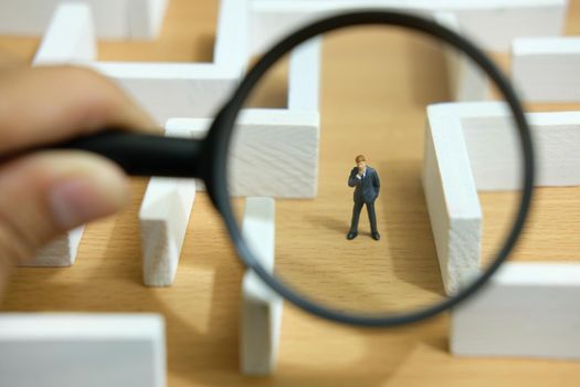 Business strategy conceptual photo - Miniature of businessman looking for solution on a labyrinth maze. Image photo