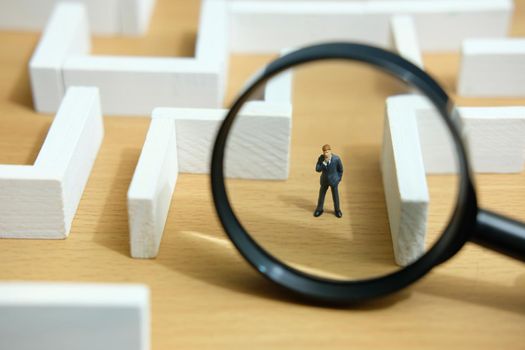 Business strategy conceptual photo - Miniature of businessman looking for solution on a labyrinth maze. Image photo