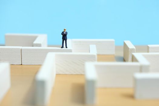 Business strategy conceptual photo - Miniature of businessman looking for solution on a labyrinth maze. Image photo