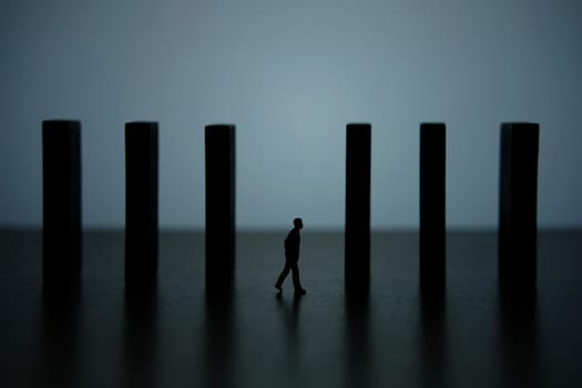 Business strategy conceptual photo – silhouette miniature of businessman walking in the middle of barrier wall. Image photo