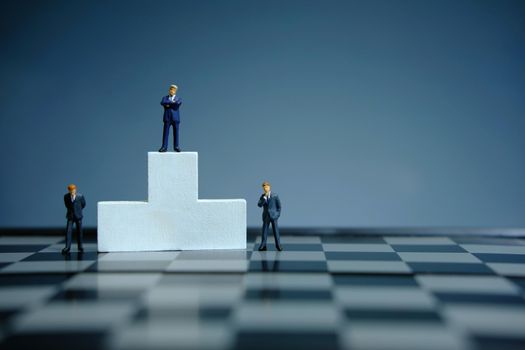 Business conceptual photo – miniature of businessman stands on wooden podium. Image photo