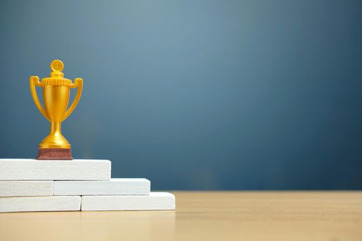 Golden trophy standing on white podium. Image photo