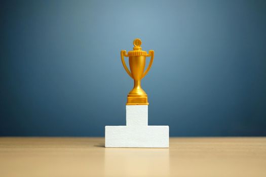 Single golden trophy on white podium. Image photo