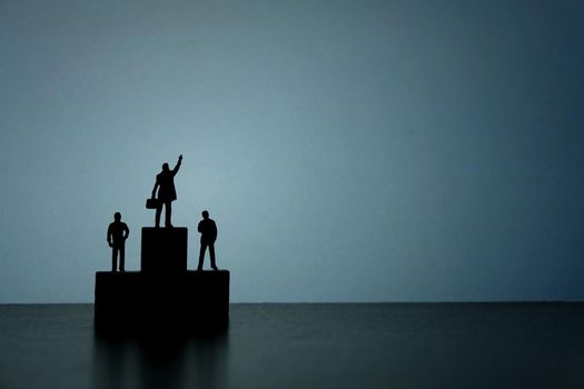 Business strategy conceptual photo - Silhouette of miniature businessman standing on podium while pointing upside. Image photo