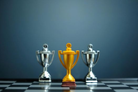 Business strategy conceptual photo – Golden trophy standing on chessboard with chess pawn. Image photo