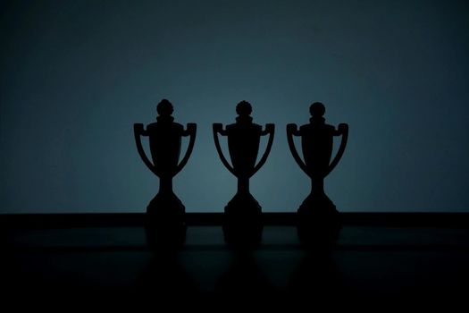 Business strategy conceptual photo – Silhouette of trophy stand in the middle of office table. Image photo