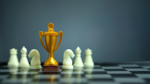 Business strategy conceptual photo – Golden trophy standing on chessboard with chess pawn. Image photo