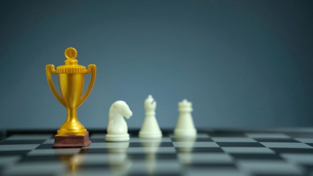 Business strategy conceptual photo – Golden trophy standing on chessboard with chess pawn. Image photo