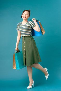 Woman wearing casual sweater on background happy enjoying shopping holding colorful bags