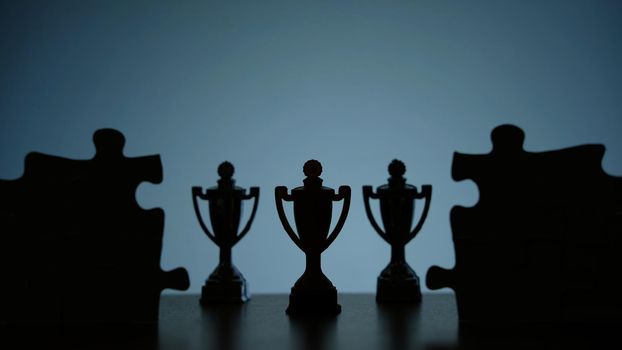 Business strategy conceptual photo – Silhouette of trophy stand in the middle of jigsaw puzzle. Image photo