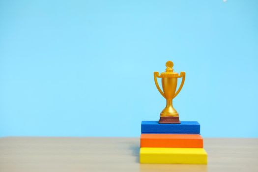 Golden trophy standing at colorful podium on wooden table. Image photo