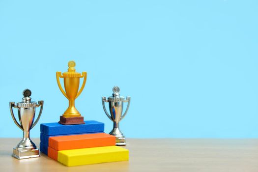 Golden trophy standing on colorful podium with two silver trophy. Image photo