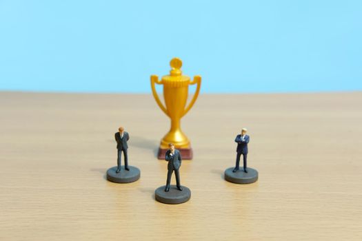 Miniature business concept - businessman lineup rank with golden trophy in the middle. Image photo