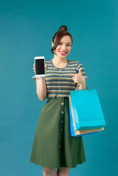 Shopping. Young smiling woman holding bag and mobile phone make her thumb up in black friday holiday