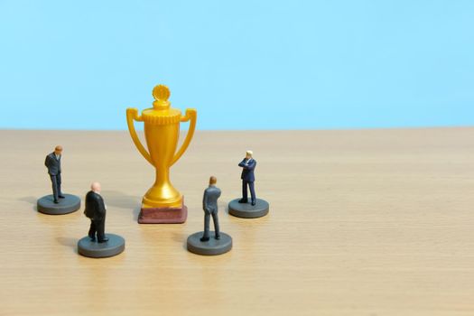 Miniature business concept - businessman lineup rank with golden trophy in the middle. Image photo