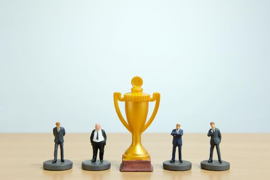 Miniature business concept - businessman lineup rank with golden trophy in the middle. Image photo