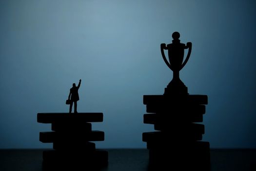 Business strategy conceptual photo - Silhouette of miniature businessman pointing on winning trophy in the podium. Image photo