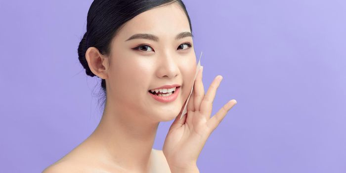 Young woman use oil paper absorbing oil from face.