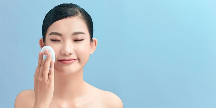 Beautiful woman applying dry powder using cosmetic cushion on her facial skin.