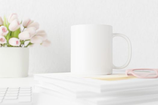 Spring white mug mockup on table with tulips and books. Coffee cup template. Blank mug printing design template. Cup mockup.