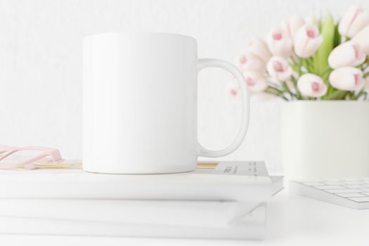 Spring white mug mockup on table with tulips and books. Coffee cup template. Blank mug printing design template. Cup mockup.