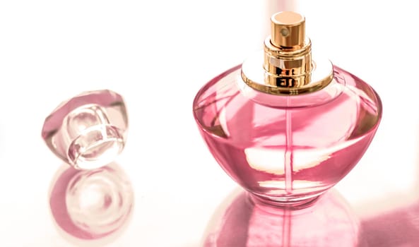 Perfumery, spa and branding concept - Pink perfume bottle on glossy background, sweet floral scent, glamour fragrance and eau de parfum as holiday gift and luxury beauty cosmetics brand design