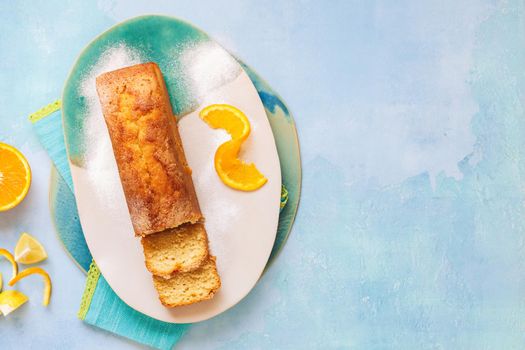 Glazed orange pound cake partly sliced and fresh citrus fruits.Top view, blank space