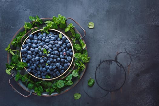 Plate of blueberries. Plate full of  ripe blueberries placed on black  rustic background. Top view, blank space