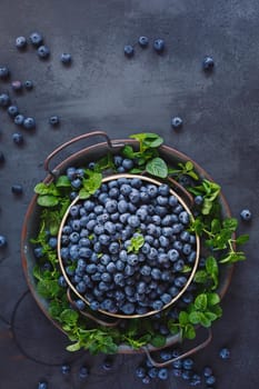 Fresh blueberries in a metal tray on a black background. Top view, blank space