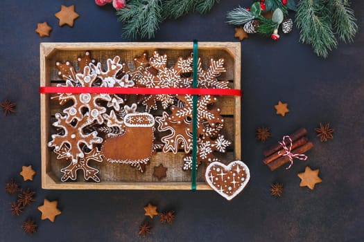 Decorated Christmas gingerbread cookies placed in wooden box with red and green ribbon on top. Top view, blank space
