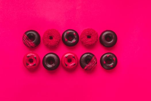 Assorted Valentine's Day Donuts. Mini  donuts with chocolate, icing and sugar sprinkles on  vibrant red backdrop. Happy Valentines day concept