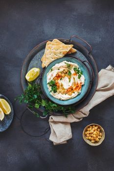 Delicious homemade chickpea hummus sprinkled with chickpeas and parsley served with pita bread. Top view, blank space