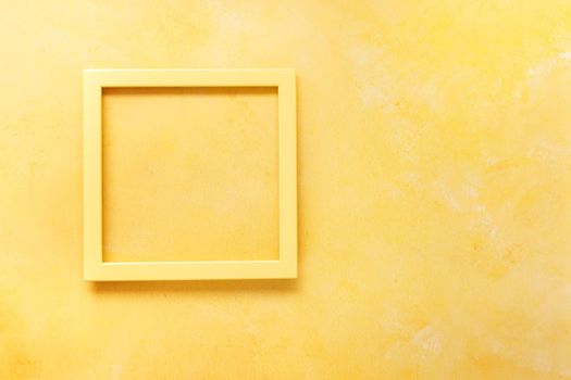 Yellow empty  frame on  rustic yellow surface. Top view, blank space