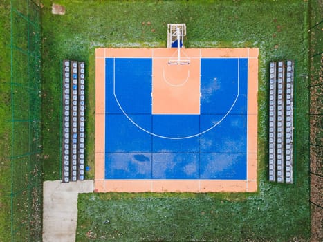 Colorful basketball  field from above. Outdoor sports ground with blue and orange surface for playing basketball,  lamps and benches for spectators