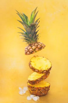 Flying  fresh ripe pineapple slices isolated on yellow background. Selective focus, copy space