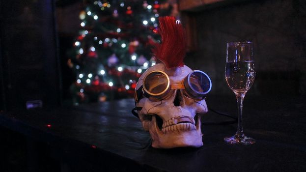 A glass of wine with a skull on the background of the Christmas tree