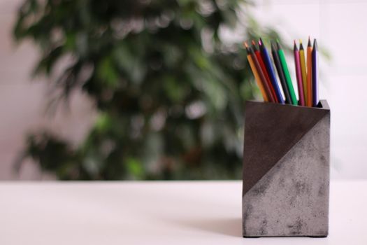 pencils in a concrete organizer. Colors on a white table