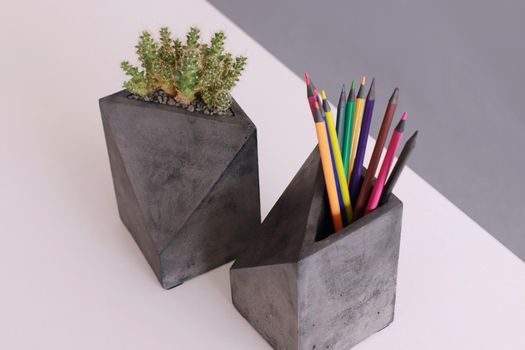 Two concrete organiser with cactus and pencils in on a white table