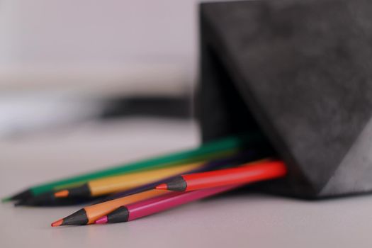 A close up of pencils in a concrete organizer. Colors. On a white table lying