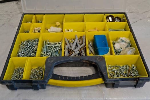 Small plastic yellow boxes with different screws and fasteners. Selective focus.