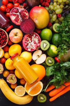 Assortment of different fruits and vegetables in rainbow colors with smoothies in bottles on dark rustic surface. Health foods, Health and wellness and Eat healthy concept