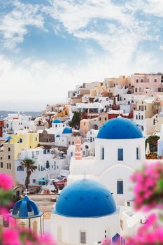 Santorini Blue domes with flowers in foreground. Greek orthodox church with blue domes in the village of Oia, Santorini, Greece