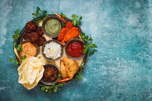 Vegetarian Thali. Indian appetizers and snacks: pakora, samosas and bhaji served with chutneys and other dipping sauces  on rustic surface. Top view, blank space