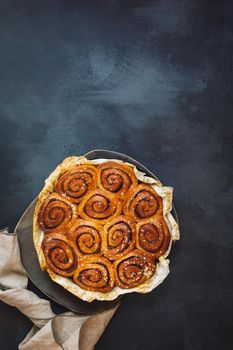 Freshly baked cinnamon rolls in a cast iron pan with sugar glaze. Top view, blank space