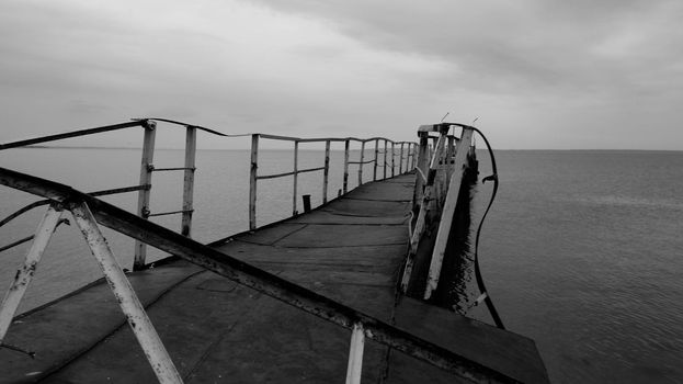 Black and white photo - broken old bridge in the sea - horizontal photo