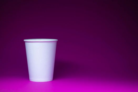 An empty white paper cup on a pink background. horizontal photo.