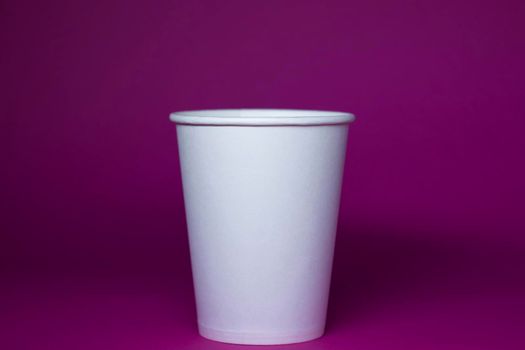 An empty white paper cup on a pink background. horizontal photo.