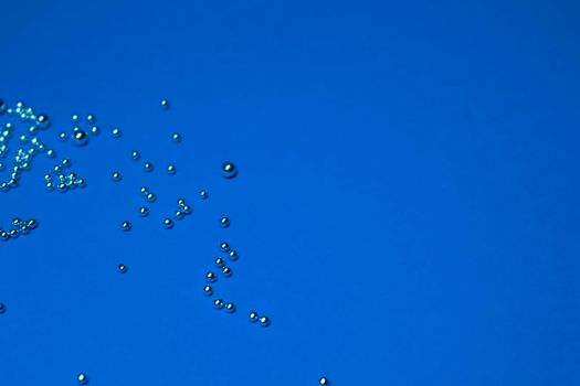 A lot of silver little balls on a blue background. Horizontal photo