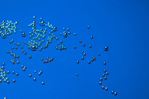 A lot of silver little balls on a blue background. Horizontal photo